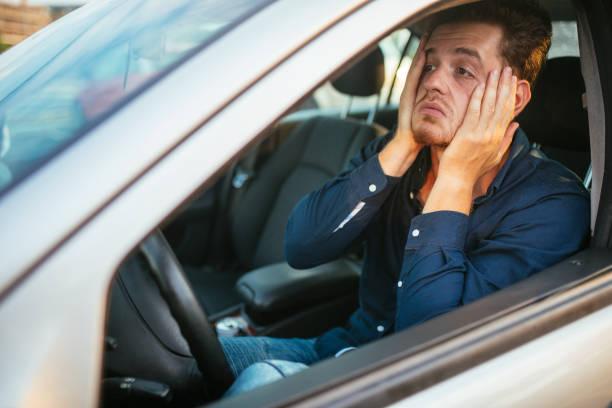 Image of a man in car behind the wheel with his head in his hands