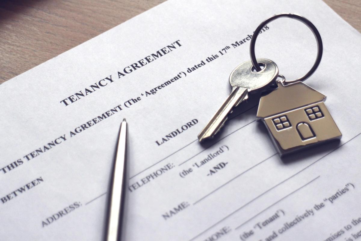 A close-up of a tenancy agreement with a pen and a house key on top of it