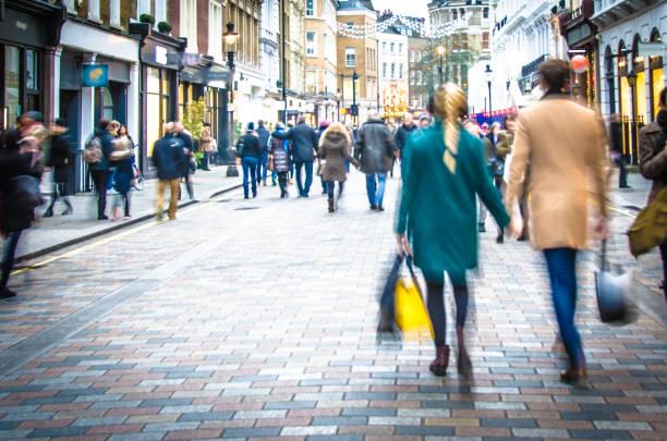 Image of a couple with shopping bags strolling down a street packed with shops