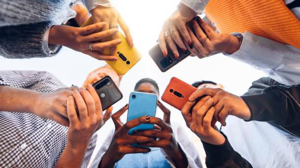 Image of people stood in a circle looking at their mobile phones