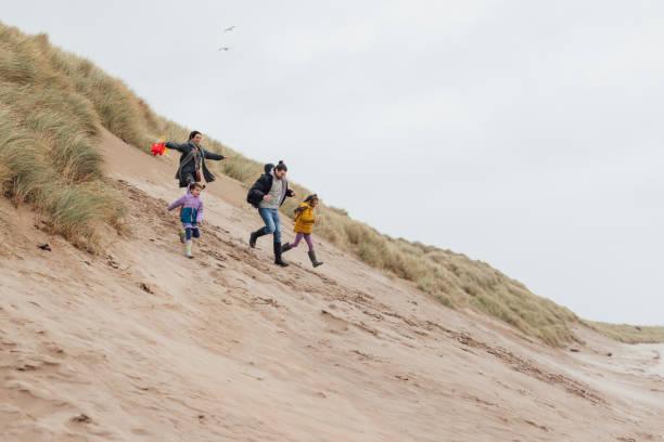 Image of a family running down a sand dune. 6 easy ways to save on your UK staycation and still have a proper holiday