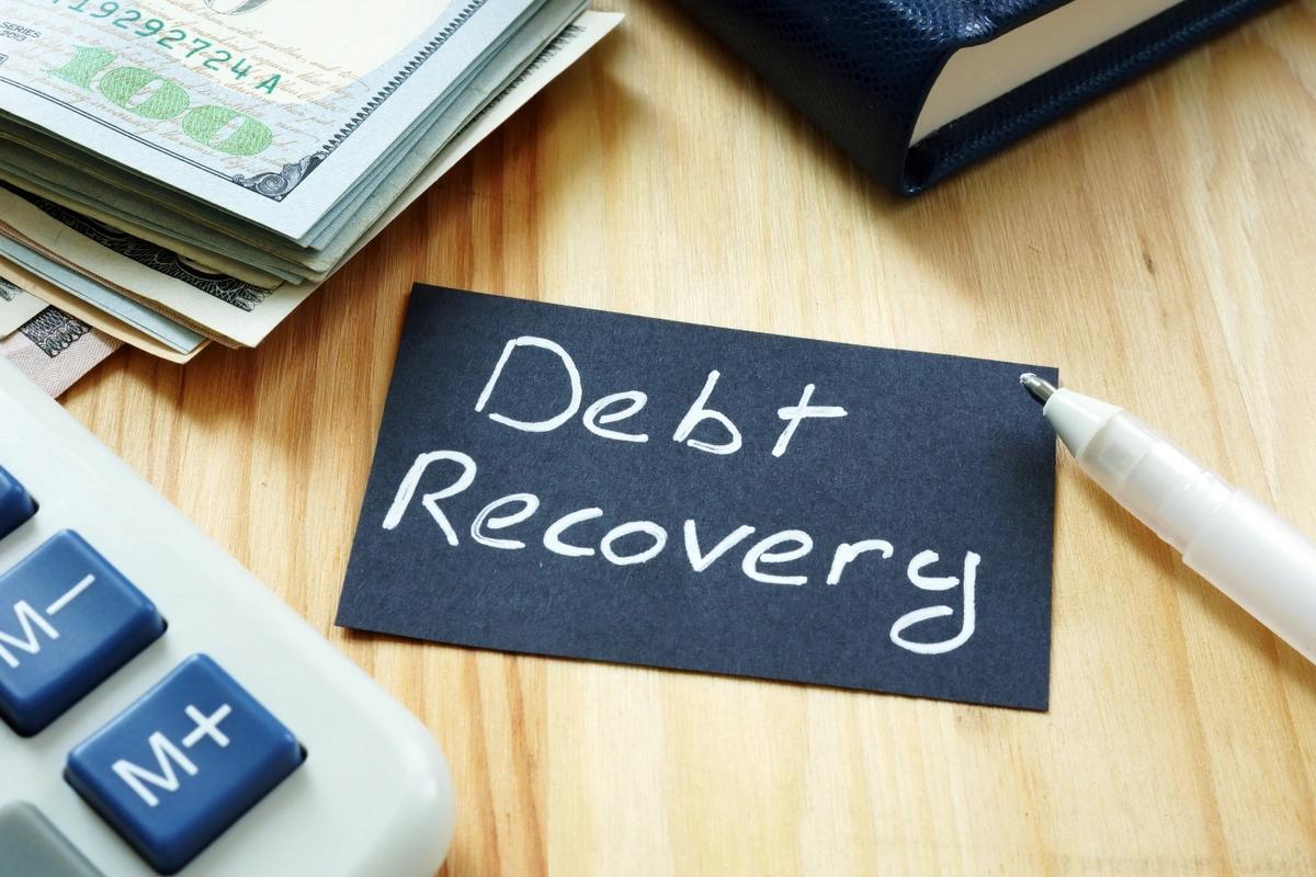 Debt recovery written on card sitting on desk