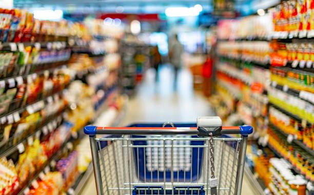 Image of a supermarket trolly in the middle of two food aisles in the supermarket