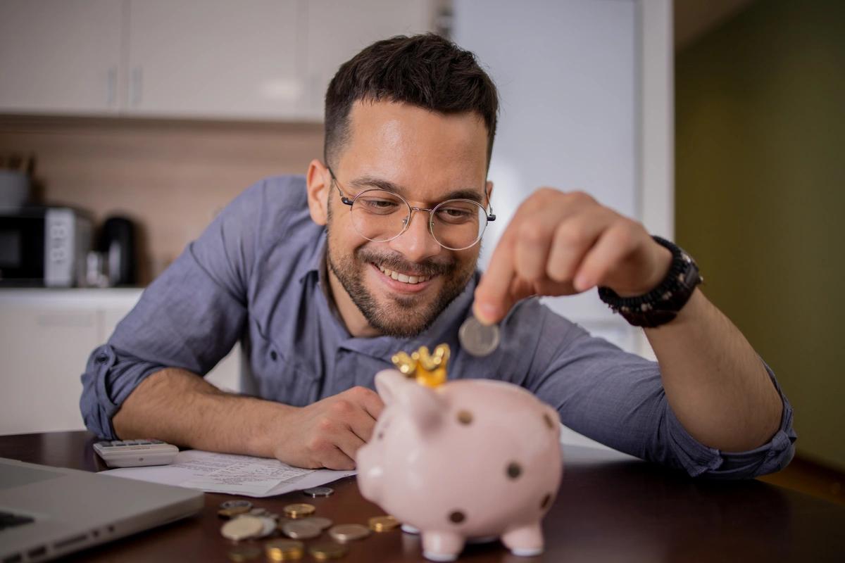 A Gen Z man drops a coin into a piggy bank