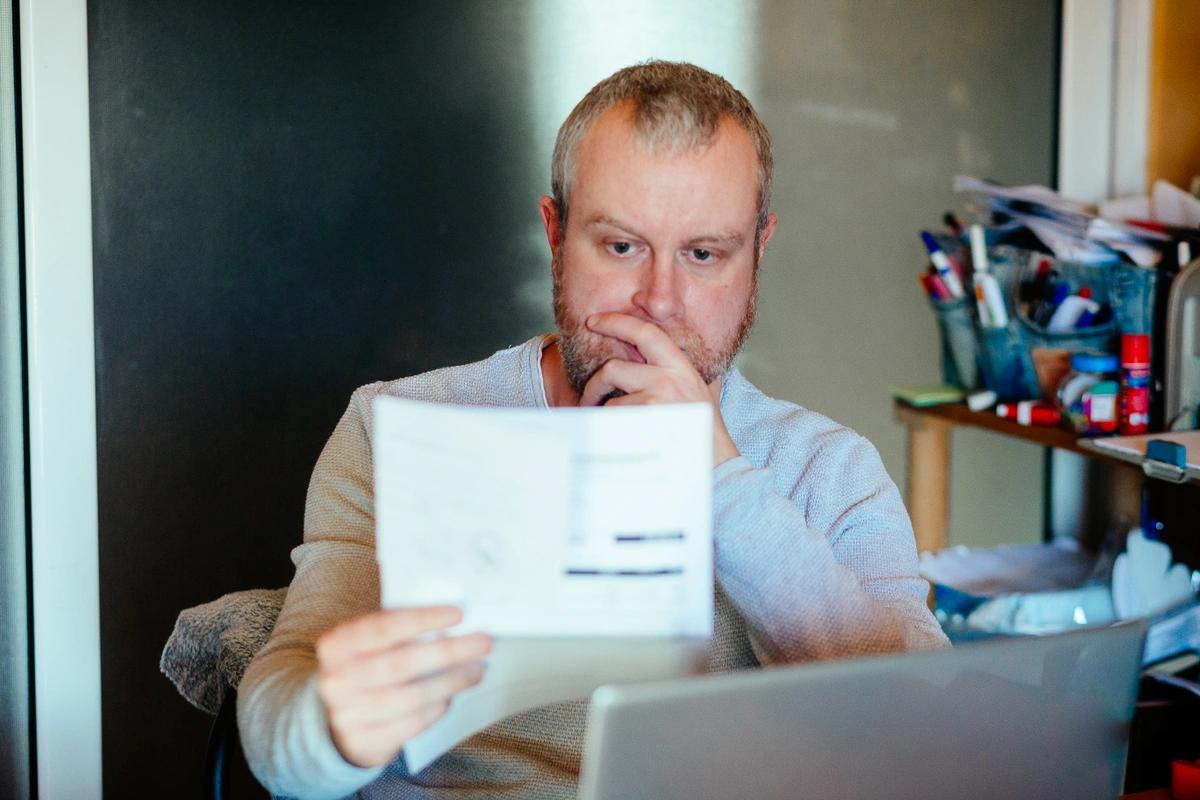 A man sitting in front of a laptop looks at a tax credit renewal letter