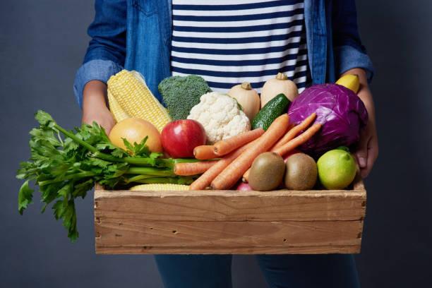 Image of a woman carrying a box filled with vegetables