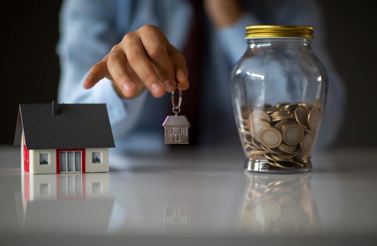 A model house, a house keyring and a jar of coins