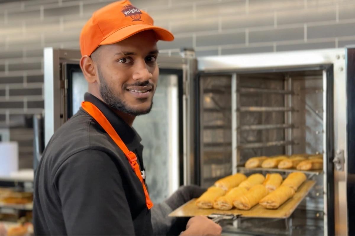 A Wrights' baker takes a tray of sausage rolls out of the oven