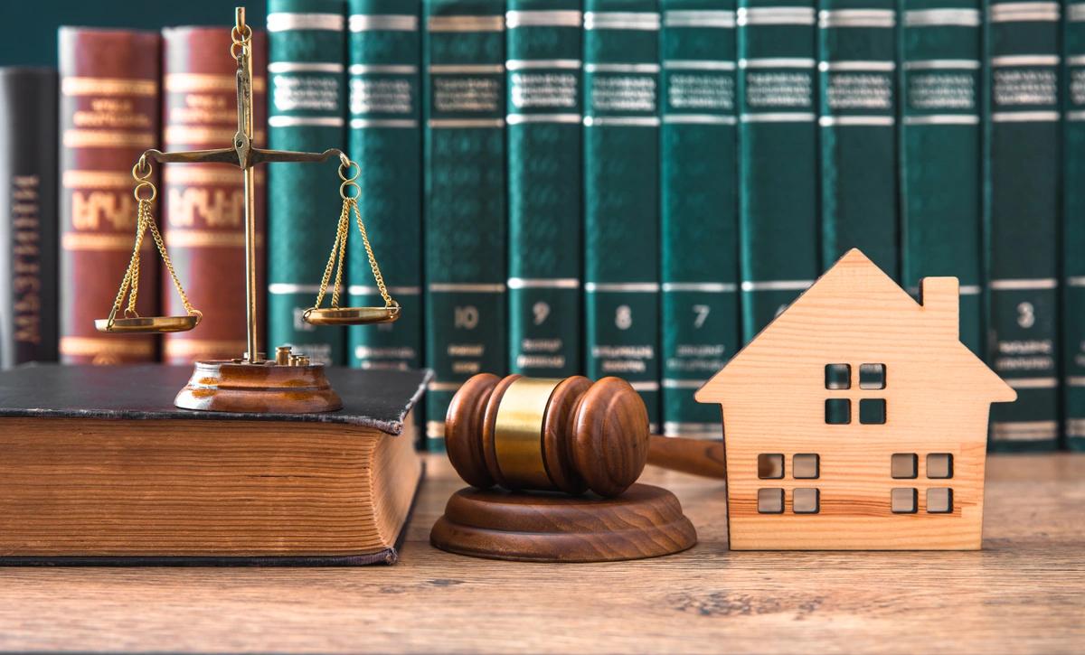 A table with a judge's gavel, some scales and a model house on it