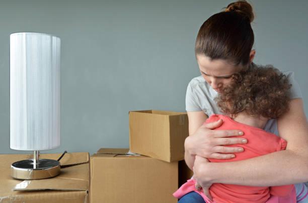 Image of a woman surrounded by packing boxes hugging a child