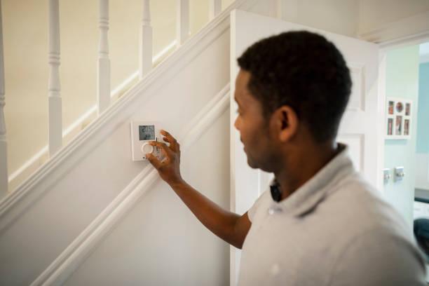 Someone changing their thermostat. 5 energy myths debunked ahead of bill price hikes