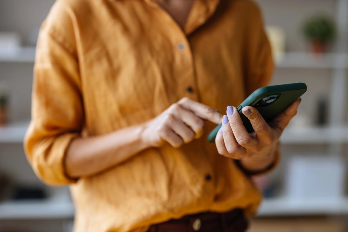 Woman in yellow shirt holds a mobile phone