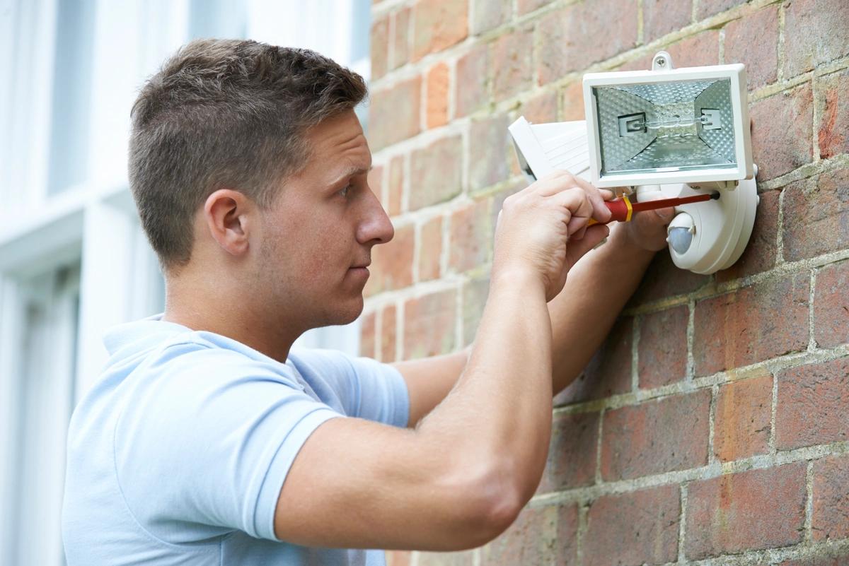 A man fitting security lights to his home