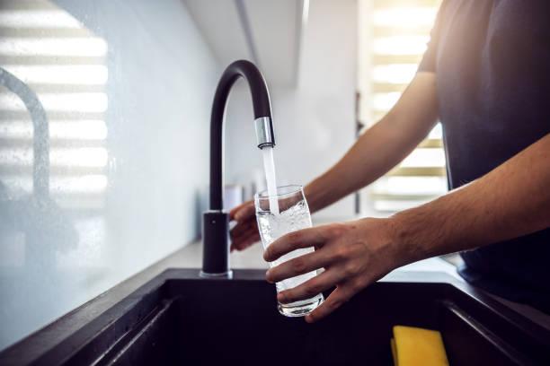 Image of a man running a tap to fill a glass of water