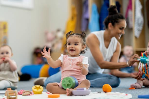 Image of a toddler surrounded by toys at nursery. Half of parents have got into debt because of childcare costs