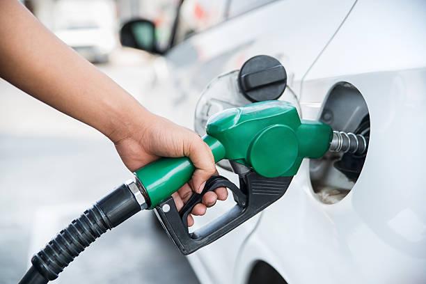 Image of a woman fill up her car at a petrol pump. Ways to save on petrol, diesel and fuel