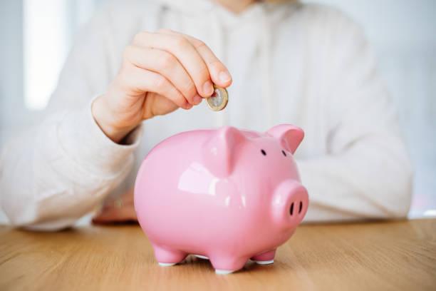Image of someone putting money in a piggy bank. Ten everyday swaps to save over £100 a month