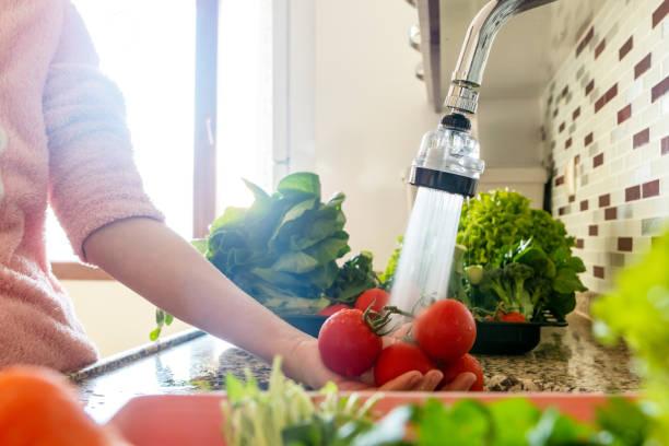 woman washing tomatoes in the sink