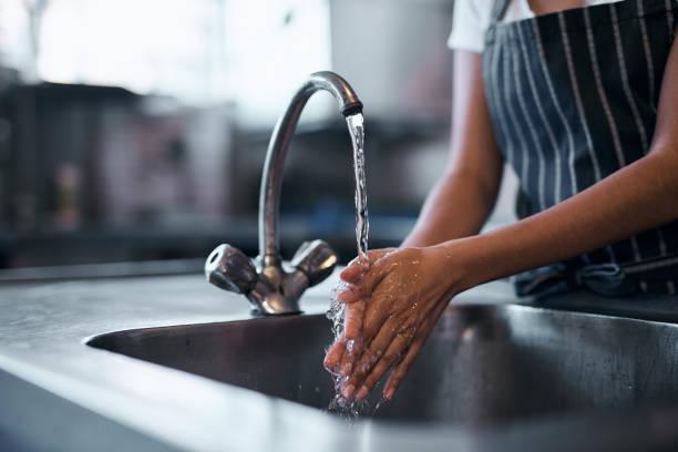 Image of a man washing his hands in a sink with running water