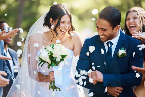 Image of a bride and groom linking arms with confetti being thrown