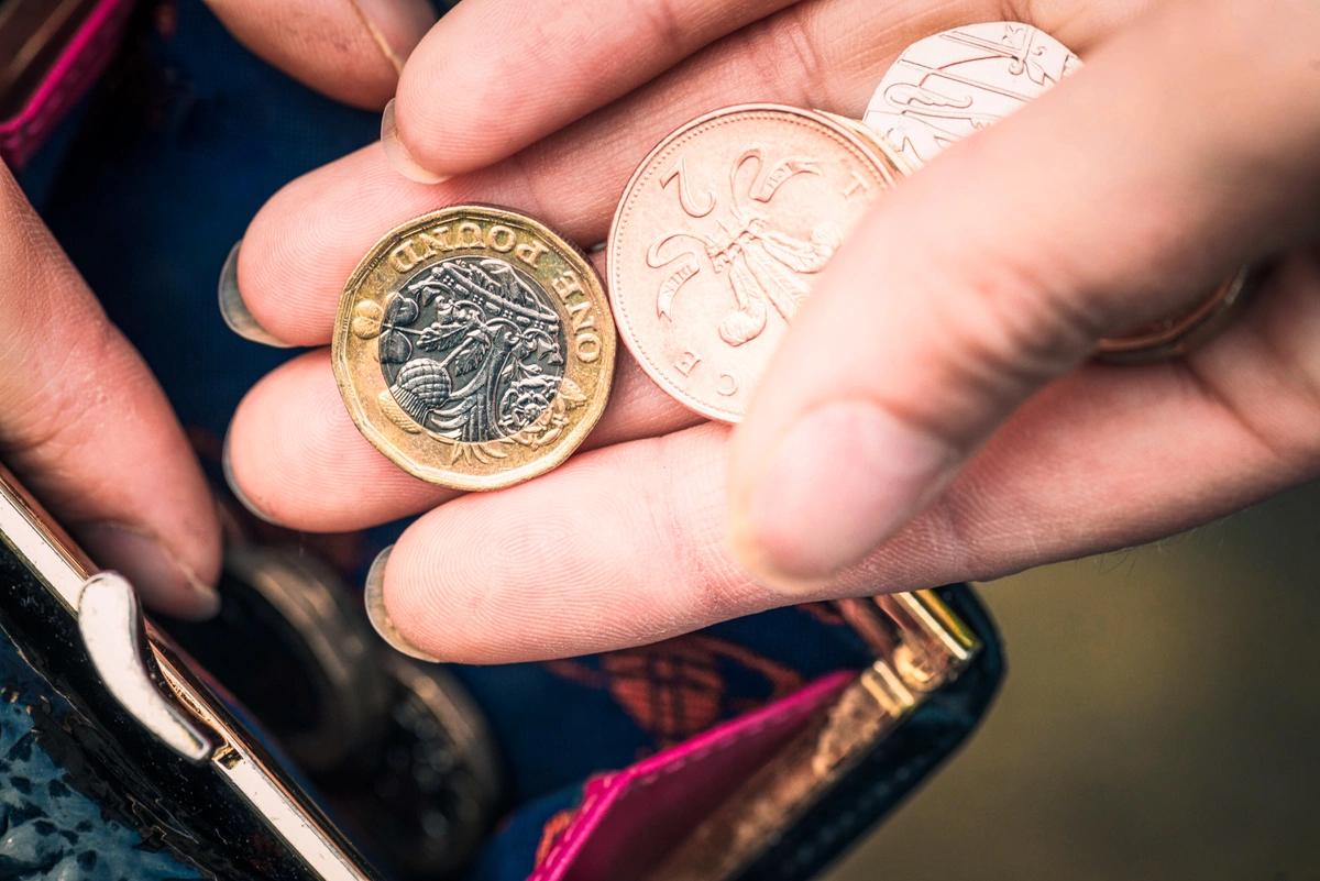 A close-up of a woman's hand putting some loose change into her purse