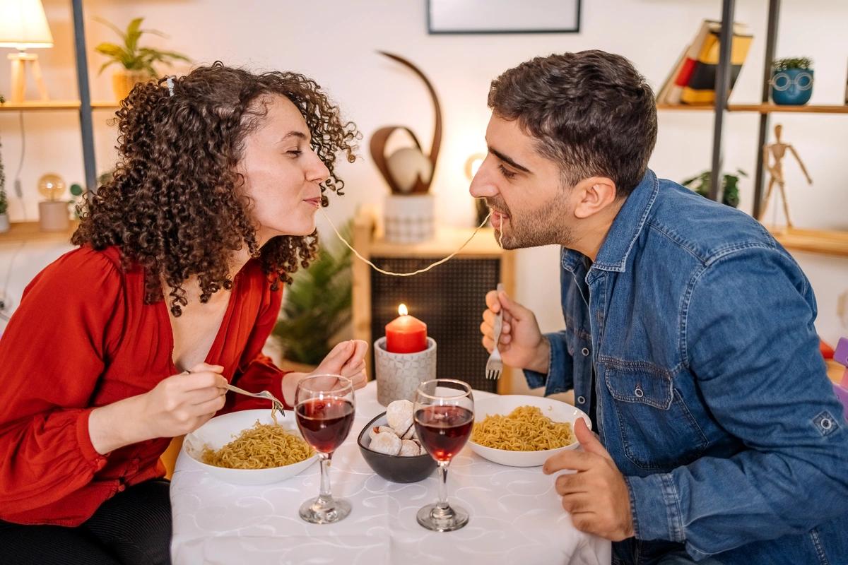 A man and a woman share a romantic meal for two at home.