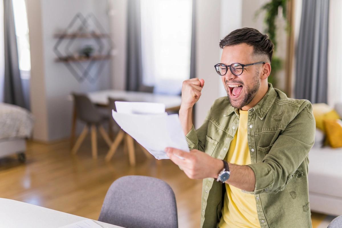 man holding paperwork with clinched fist celebrating