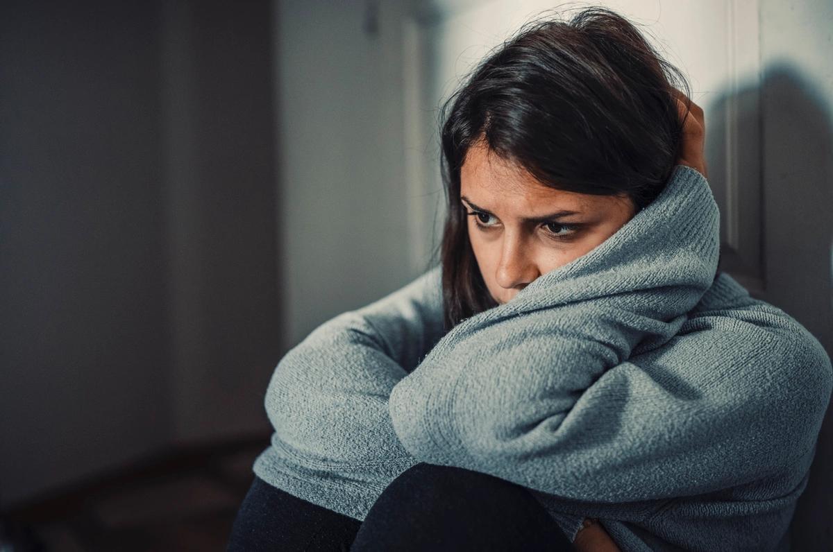 A young woman with head in arms who looks stressed