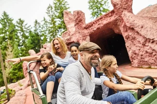 Image of a family on a theme park ride. 12 ways to have a cheaper summer holiday with the kids. Free bus travel, kids eat free deals and free days out — how to save money in the school summer holidays 2026