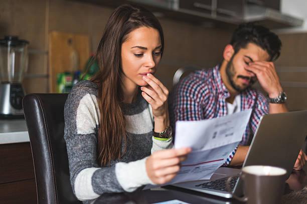 Image of a couple reading over bills and looking worried