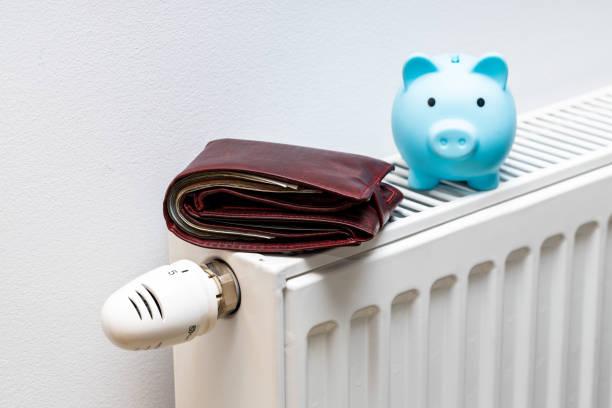 Image of a radiator with a blue piggy bank on top and a wallet. Prepayment meter debt - what help is available for paying energy bills