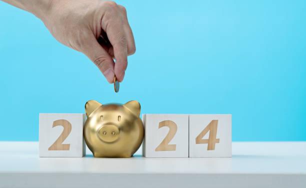 Image of 2024 in cubes with the '0' being a gold piggy bank and someone dropping a coin into it