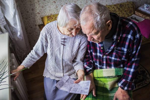 Image of an older couple huddled together with the wide showing her husband the bills