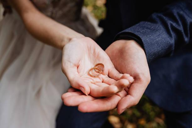 Image of a bridge and groom with their hands on top of each other cupping two gold wedding bands. March tops the month for marriage allowance claims