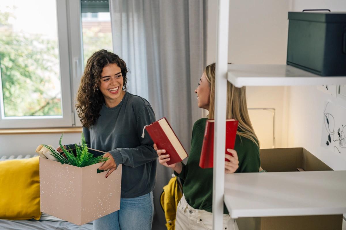 Students in dorm room with box ready to move in