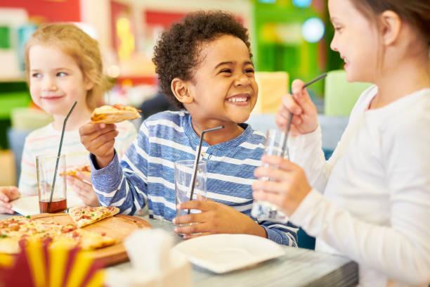 image of three children eating pizza in a restaurant
