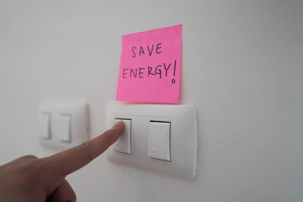 Light switches with a post-it note above them saying 'save energy!'