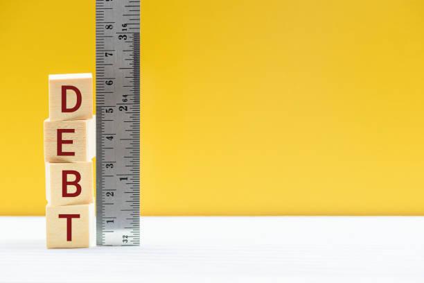 Building blocks spelling out 'debt' with a ruler next to it measuring how much debt. Eight signs you have a problem with debt