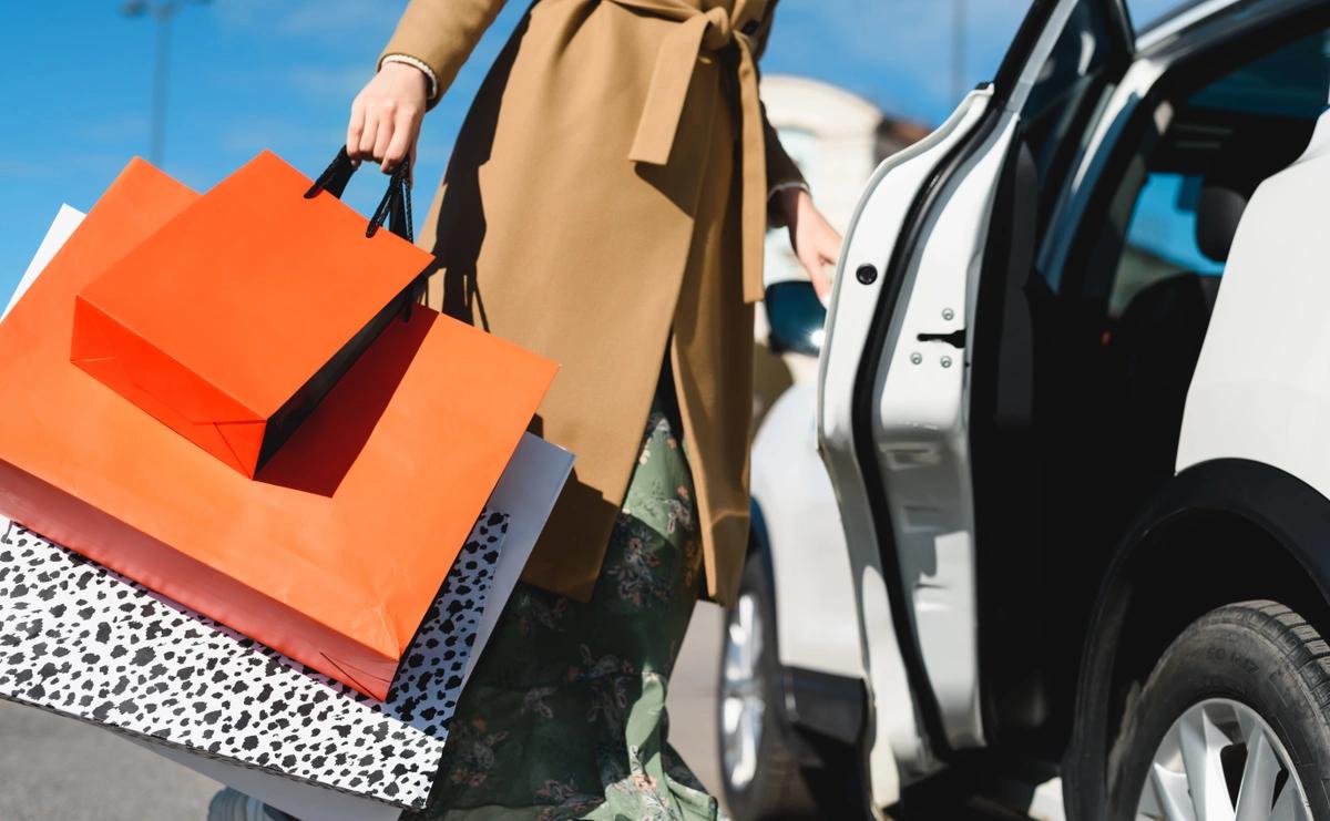 A woman getting into her car with lots of shopping bags