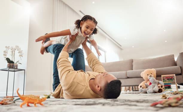 Image of a parent lay on the floor with a child on top of them playing a game