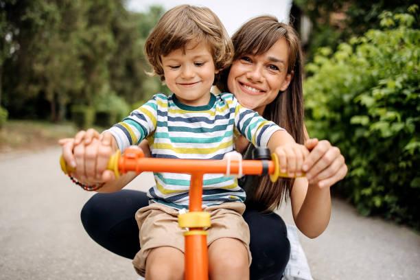 Image of a mum crouched down behind her child on a bike