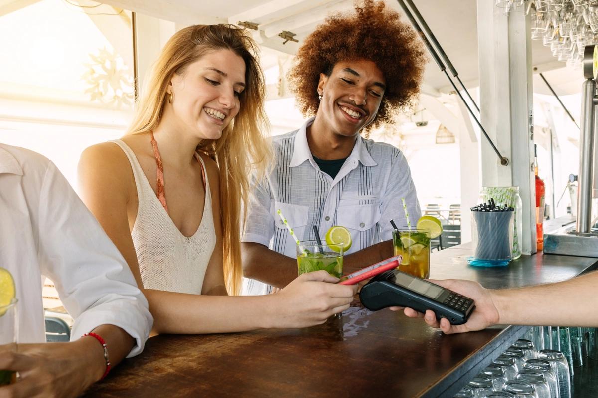 A young couple pay for drinks at the bar