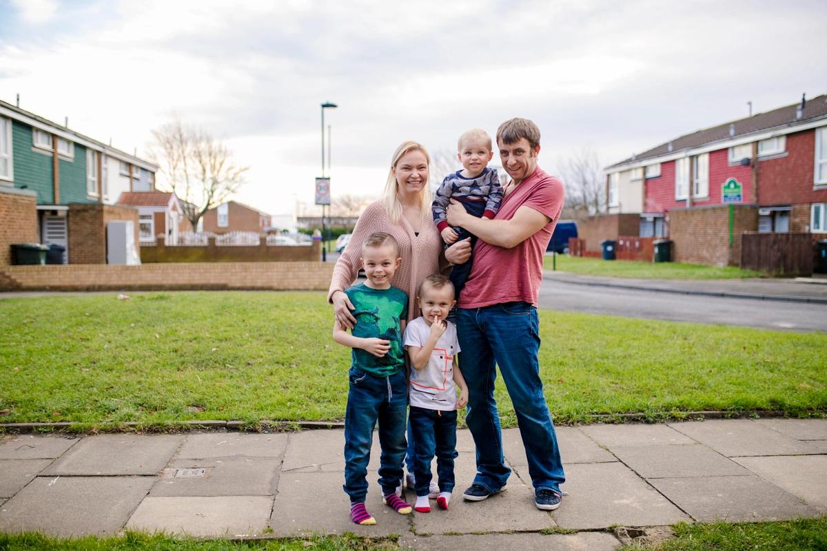 A mum and dad with three young children on the street outside their home