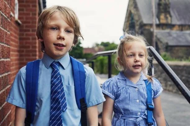 Image of two children walking to school in uniform.. The charity shops where parents could find FREE or cheap school uniform this summer