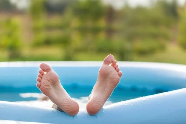 Image of feet sticking out of a paddling pool. 6 heatwave mistakes that could be costing you cash. Britain is baking, but staying cool doesn't have to leave you out of pocket
