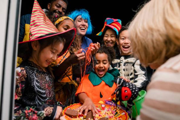 image of a group of children dressed up in Halloween outfits taking sweets off a lady