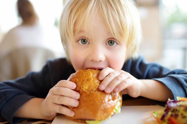 image of a toddler tucking into a huge sandwich roll