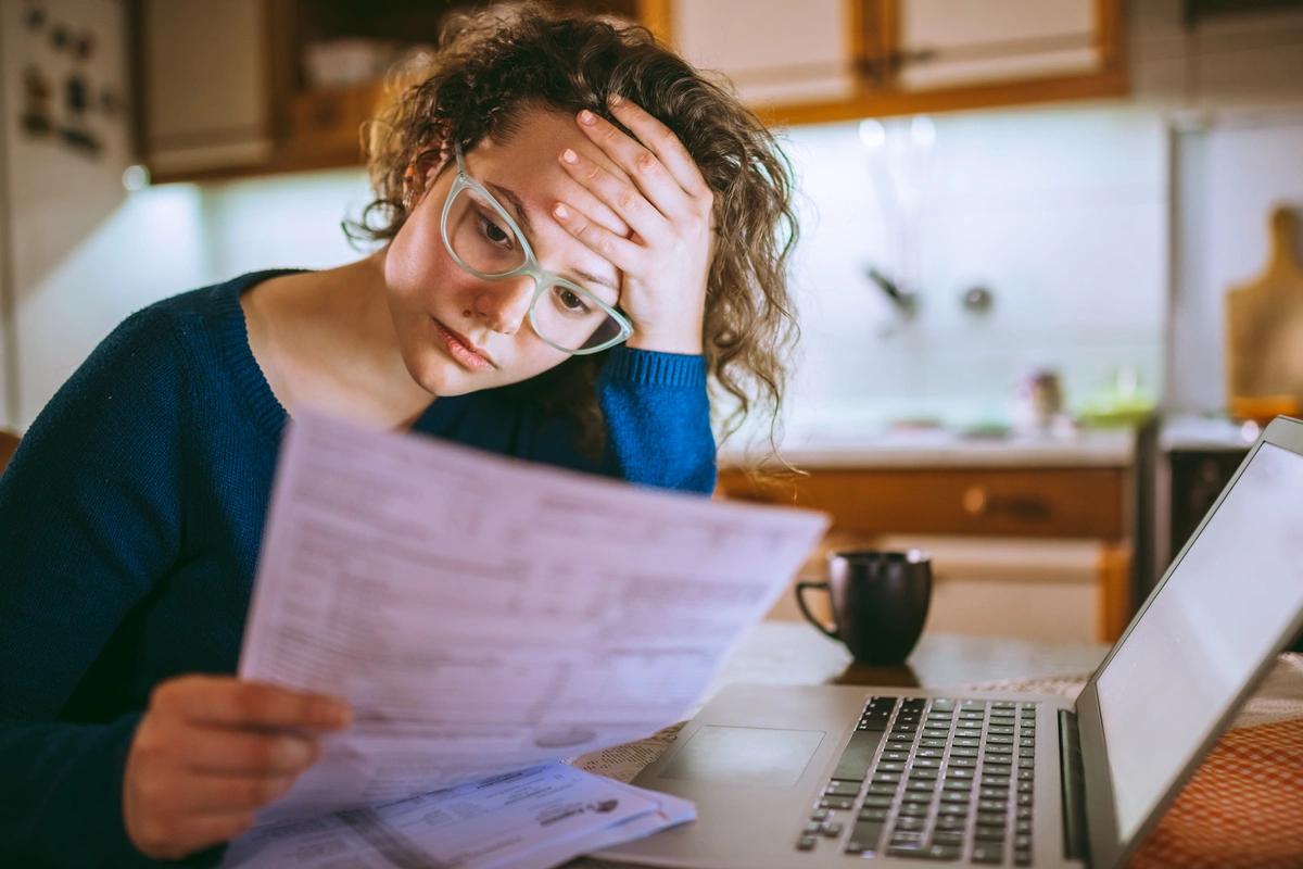 A worried looking woman going through her bills after Christmas