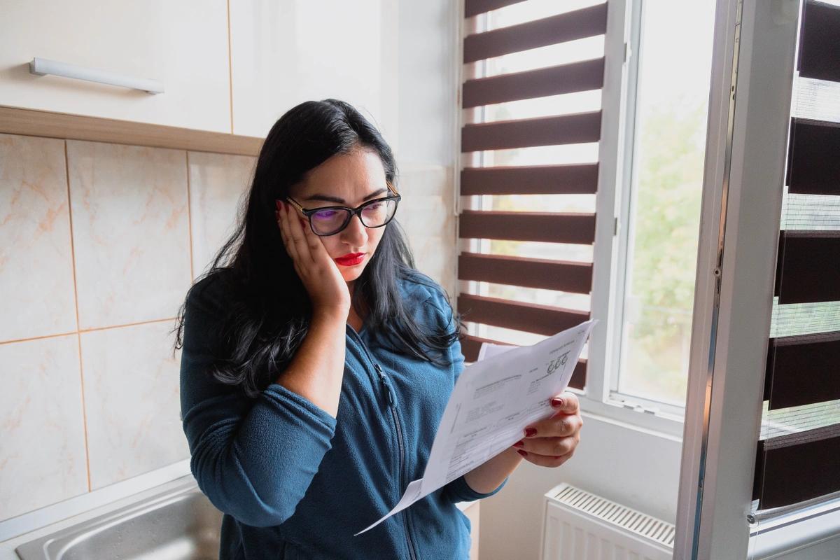 A worried-looking woman reading her energy bill