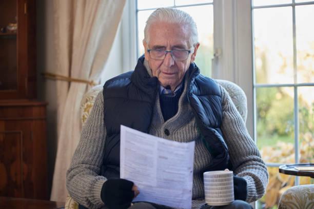 Image of a pensioner wrapped up warm looking at bills
